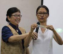 手工班老師李細珠示範如何將包裝袋裁剪成細條狀。【攝影者：董燕榮（慈奐）】