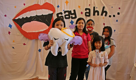 「牙齒與口腔健康展覽」的一系列活動吸引了不同年齡層的民眾參與。圖為孩子們拿著牙齒道具開心地的布幔前留影。【攝影者: 許薇盈（懿礽）】