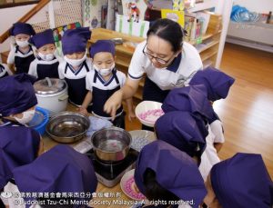 老师示范煮汤圆过程，孩子在一旁认真聆听。 （摄影者：邝奕谦）