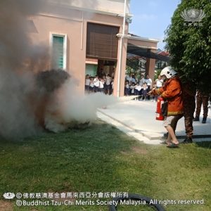 老师们穿上消防员装备，实际练习如何使用灭火器把火扑灭。