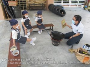 老师在讲解用火炭煮食物需要注意的安全。